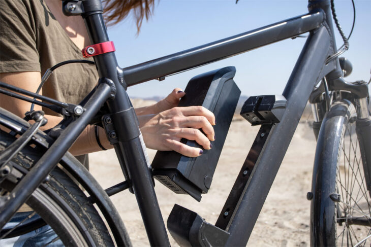 Frau wechselt einen E-Bike-Akku am Fahrrad.